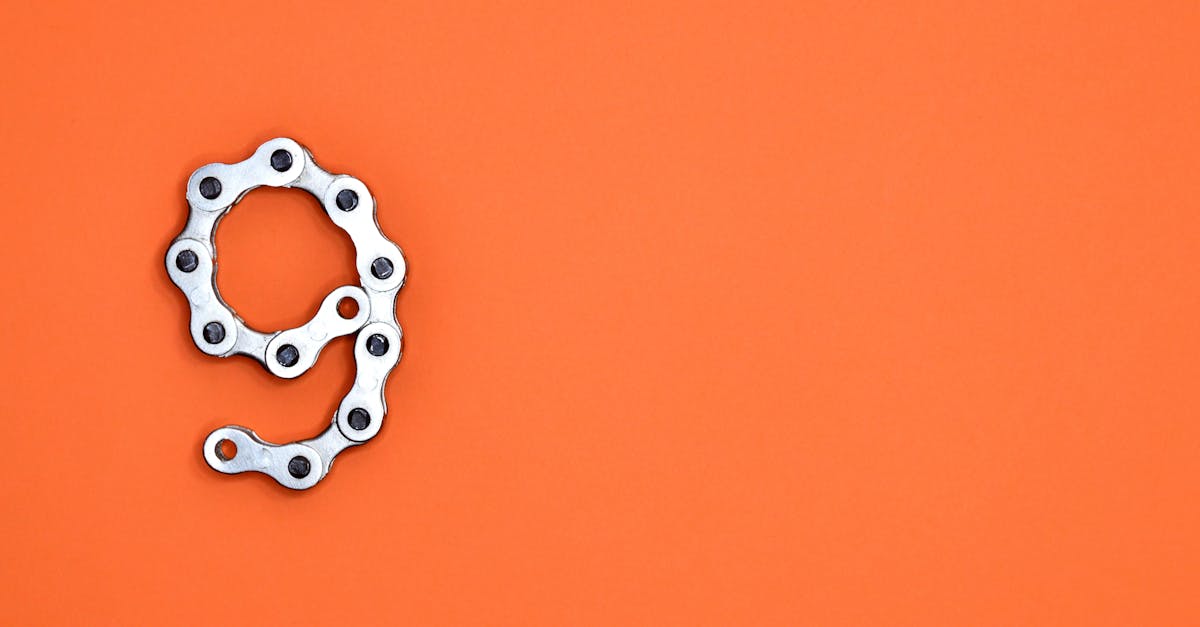 A metal chain shaped like the number nine against a vibrant orange background with copy space.