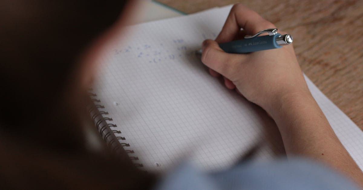 A student writes mathematical notes in a notebook using a pen, focus on studying.