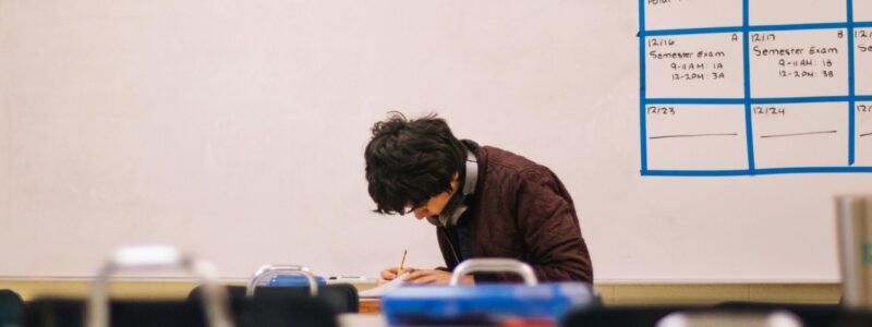 A high school student studying and solving problems in a classroom setting.