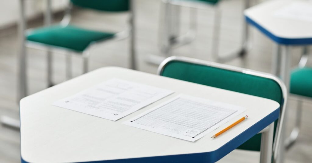 A close-up of an empty classroom desk with exam papers and a pencil, highlighting education and testing environment.
