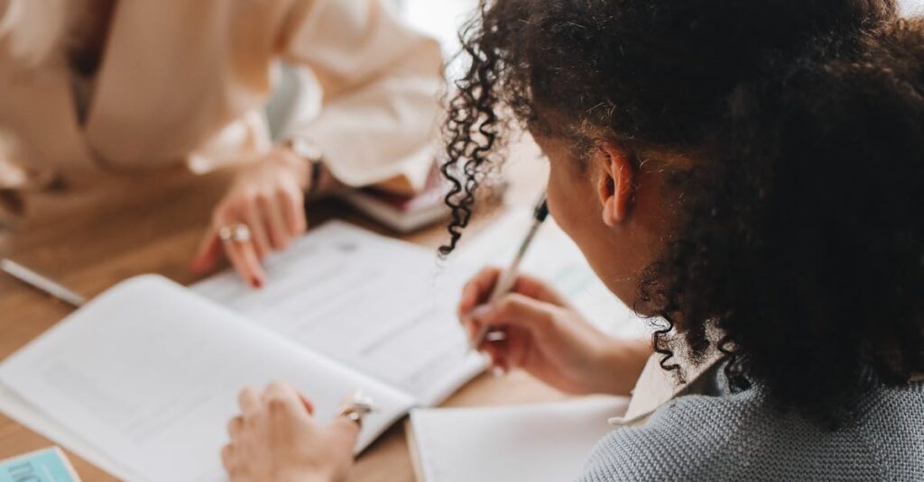 Two women engaged in discussion and study at a table with books and notepads.