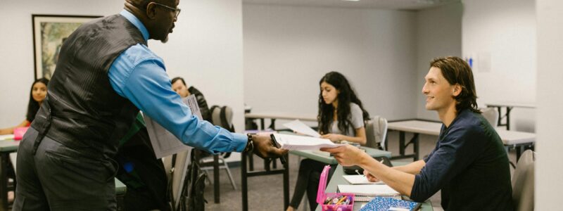 A teacher engaging with students in a university classroom, promoting active learning.