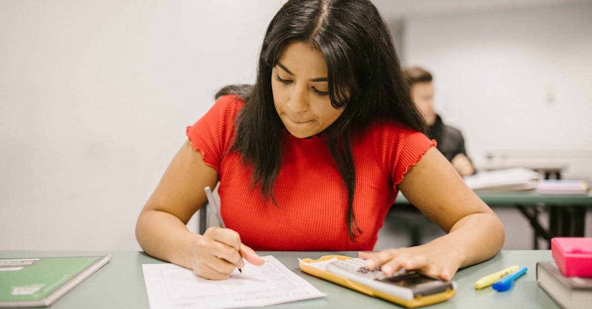 Focused college student using a calculator during an exam. Indoor educational setting.