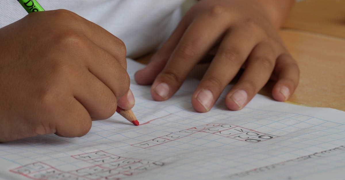 Close-up of a student writing math equations in a notebook with a pencil indoors.