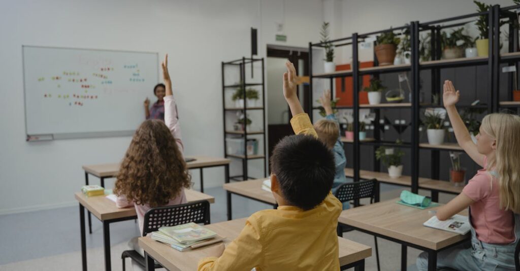 Diverse group of students raising hands in a vibrant classroom setting with teacher at front.