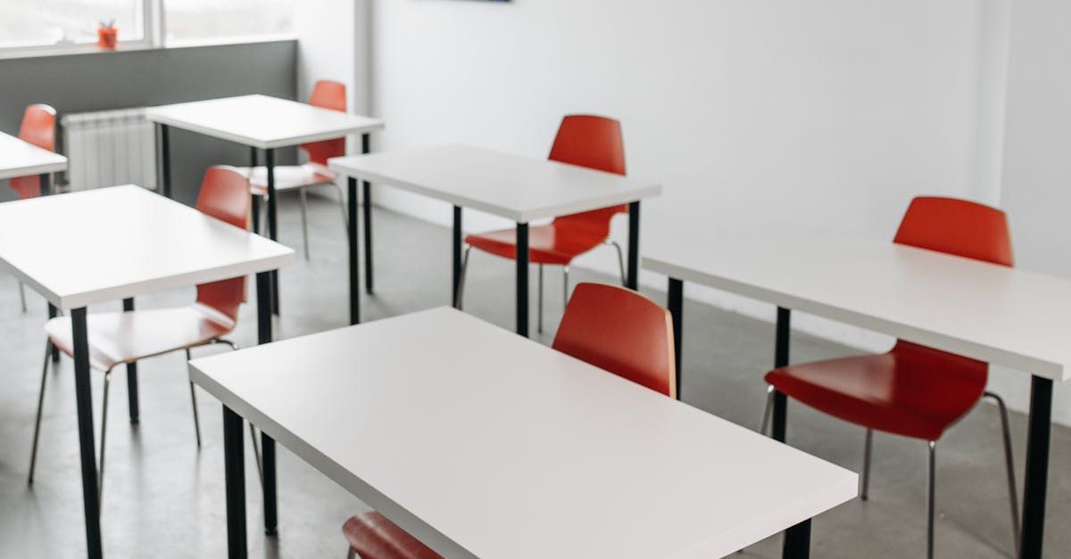 Contemporary classroom interior with red chairs and white desks arranged in rows.
